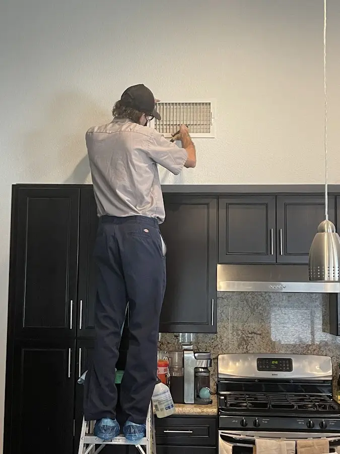 Technician inspecting an air vent during HVAC service in Dearborn